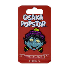 Osaka Popstar enamel pin featuring a blue zombie with a glitter hat design