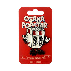 Kawaii black metal enamel pin of a cartoon popcorn box character with eyes and hands