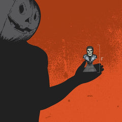 Silhouette holding Misfits Fiend mini bust against an orange background